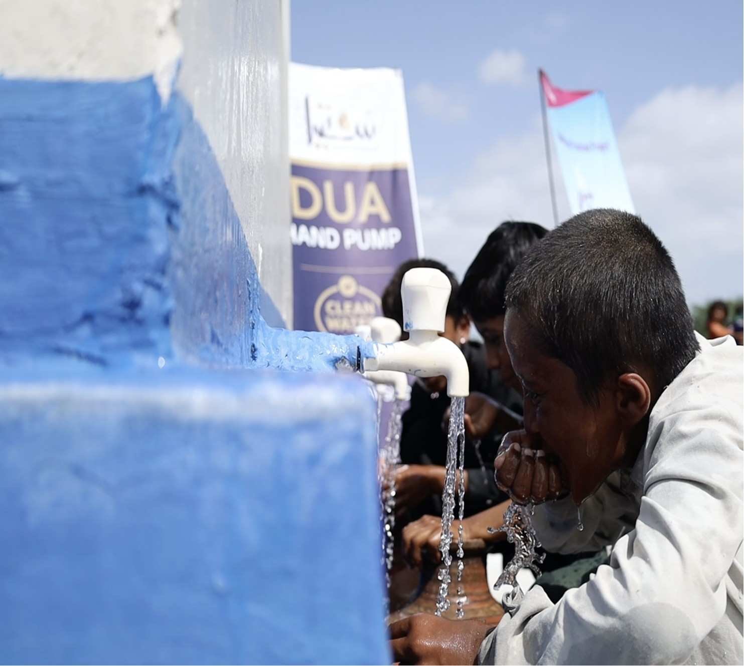 Child drinking water from Suqya Waters community pump