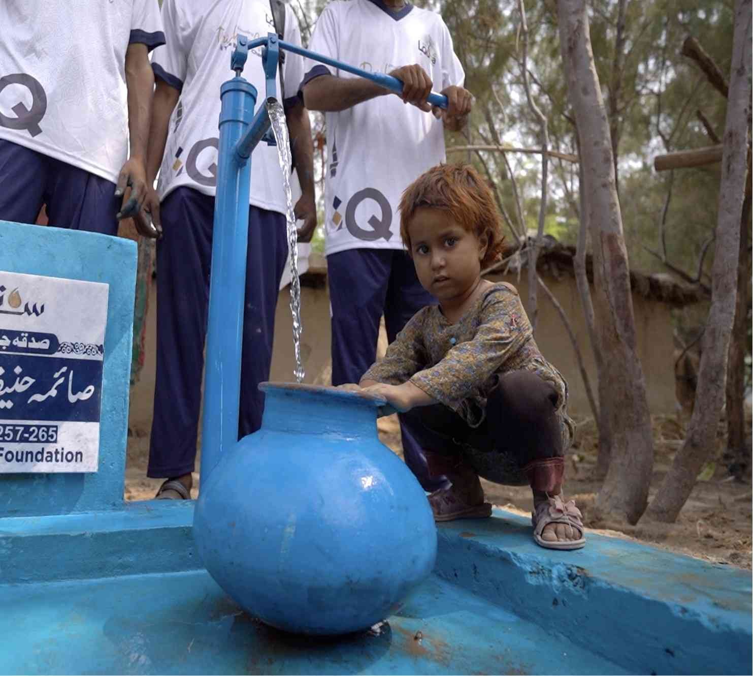 Girl filling water container at Suqya Waters installation